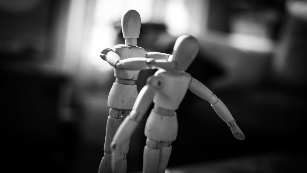 Two wooden toys shaped like humans fighting. Photo.