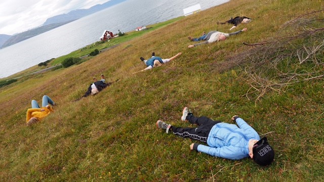 People lying in the grass by the sea. Photo.